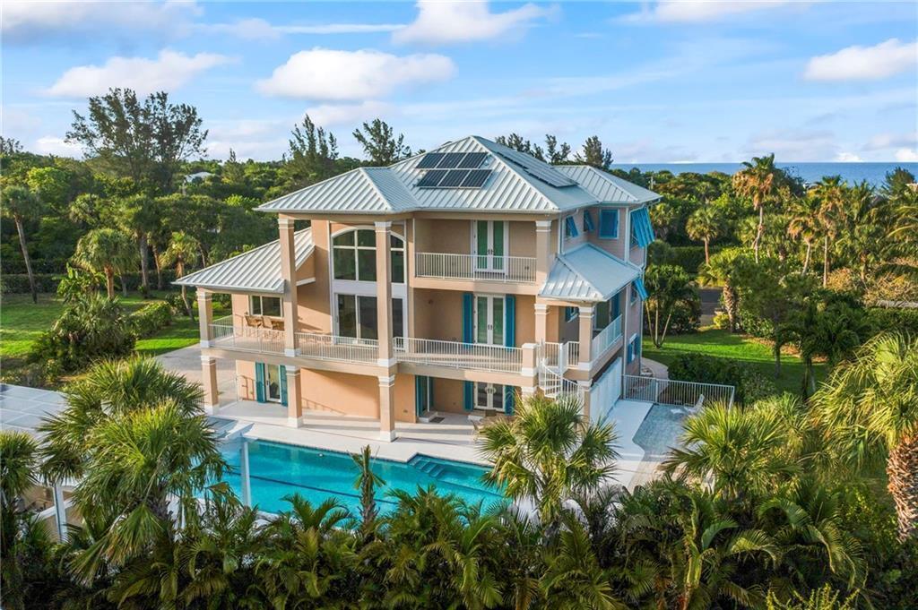 An aerial view of a three-story tan house with a pool and solar panels — 2275 Genesea Lane, Vero Beach FL 32963, VERO BEACH, FL
