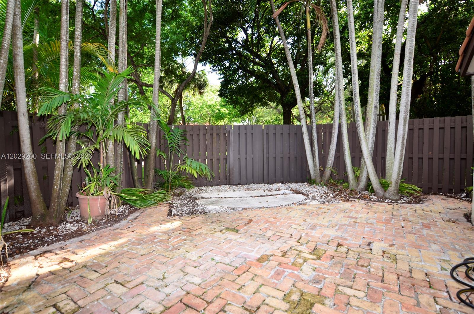 A brick patio features a potted palm tree and a wooden fence backdrop — 13224 SW 111th Ter # 3, Miami FL 33186, MIAMI, FL