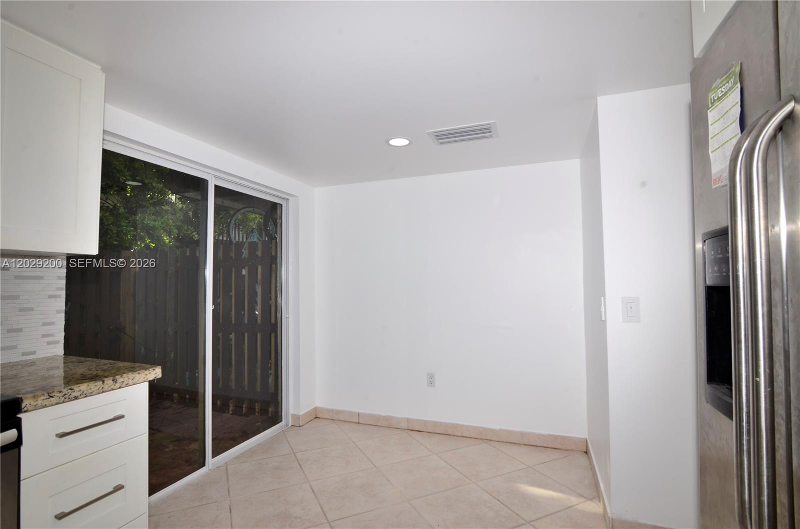 A kitchen dining area features white cabinets, tile flooring, and a sliding glass door — 13224 SW 111th Ter # 3, Miami FL 33186, MIAMI, FL
