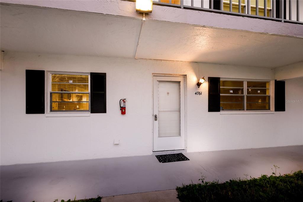 An exterior view of a white building entrance with a door, windows, and a fire extinguisher — 4761 INDEPENDENCE DRIVE UNIT 4761, BRADENTON, FL