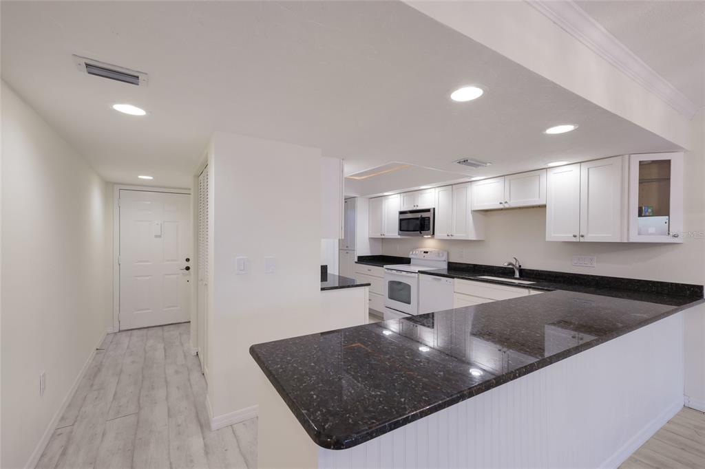A kitchen with white cabinets, dark granite countertops, and light wood-look flooring — 4761 INDEPENDENCE DRIVE UNIT 4761, BRADENTON, FL