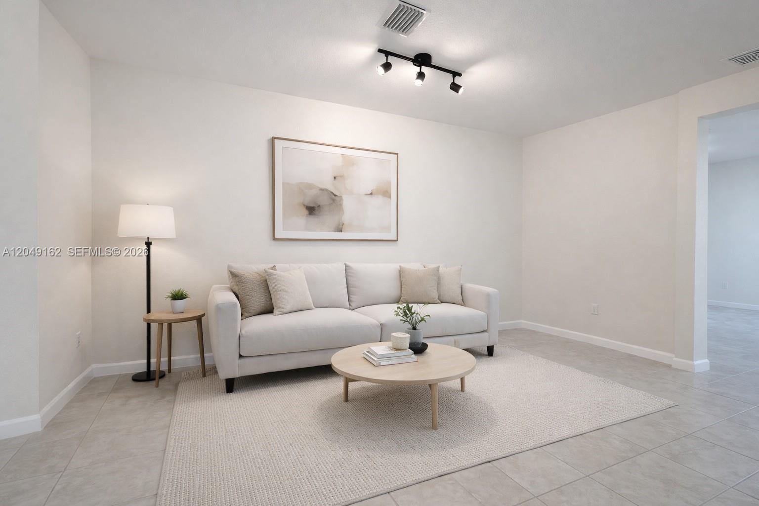 A living room features a light-colored sofa, a round coffee table, and a neutral rug — 323 NE 208th Ter # 0, Miami FL 33179, MIAMI, FL