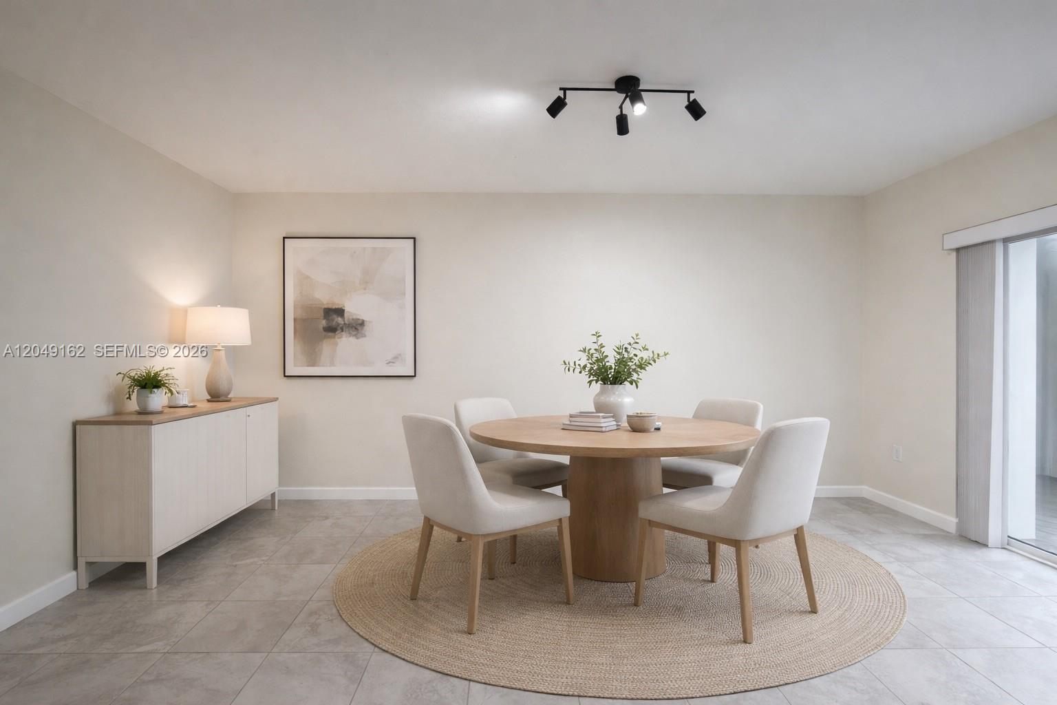 A dining room features a round wooden table, four chairs, a sideboard, and tile flooring — 323 NE 208th Ter # 0, Miami FL 33179, MIAMI, FL