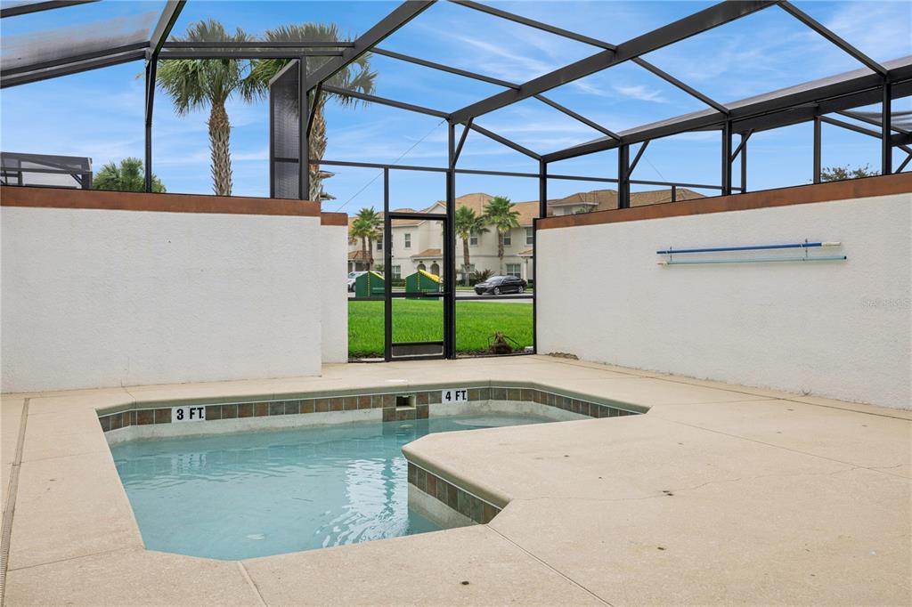 A screened-in patio features a small swimming pool with depth markers and concrete decking — 1584 SLICE WAY, DAVENPORT, FL