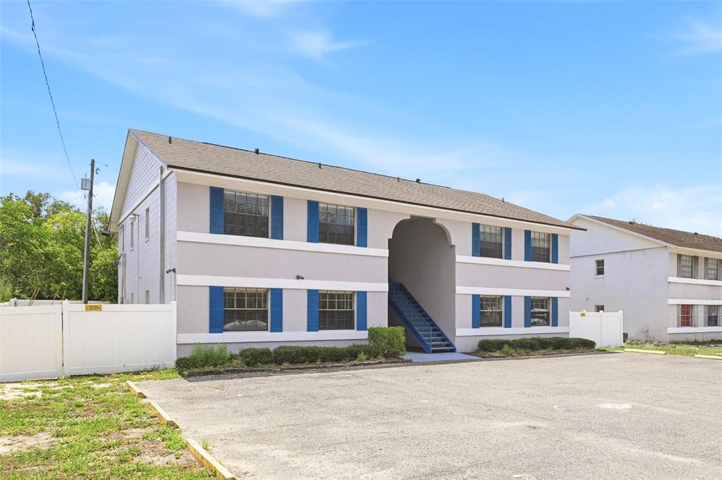 A two-story apartment building with a central stairwell and blue shutters sits by a parking lot — 10 N FAIRFAX AVENUE UNIT 10, WINTER SPRINGS, FL