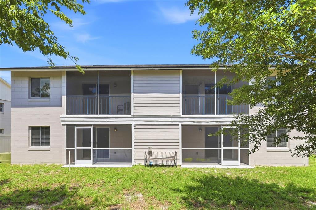 The rear exterior of a two-story apartment building features screened-in balconies and patios — 10 N FAIRFAX AVENUE UNIT 10, WINTER SPRINGS, FL