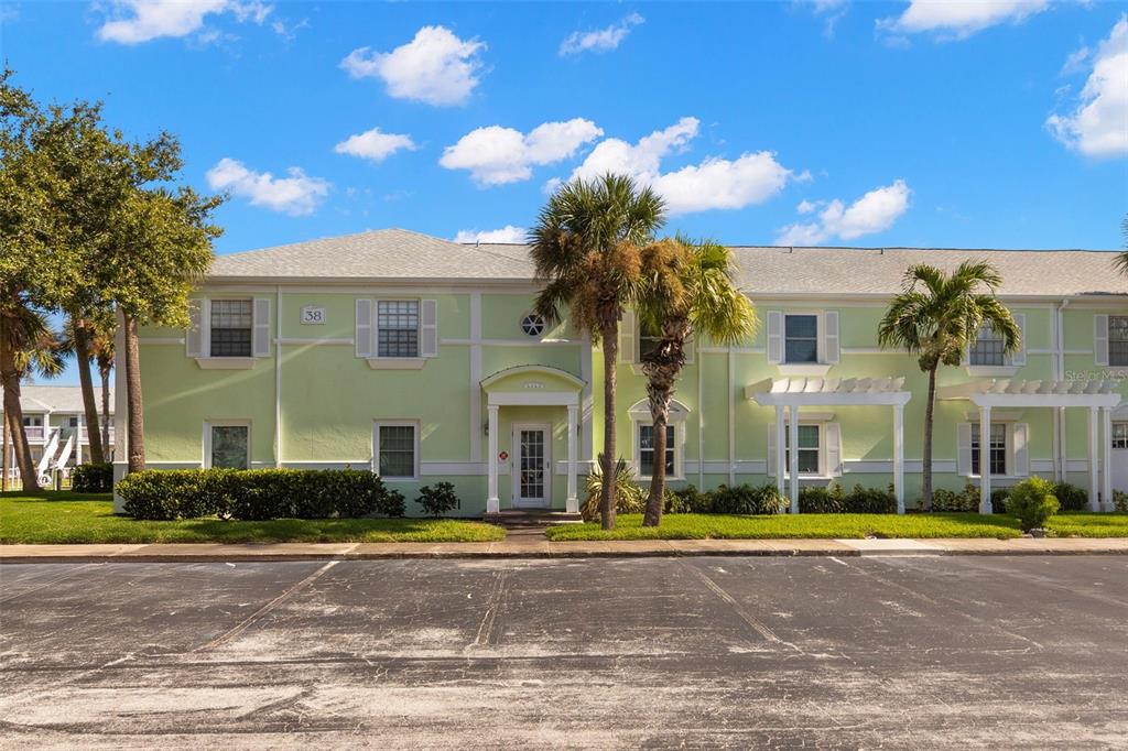 A two-story, light green apartment building features a central entrance and palm trees outside — 5243 BEACH DRIVE SE UNIT B, ST PETERSBURG, FL