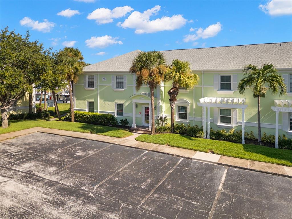 A two-story light green apartment building with a parking lot in the foreground — 5243 BEACH DRIVE SE UNIT B, ST PETERSBURG, FL