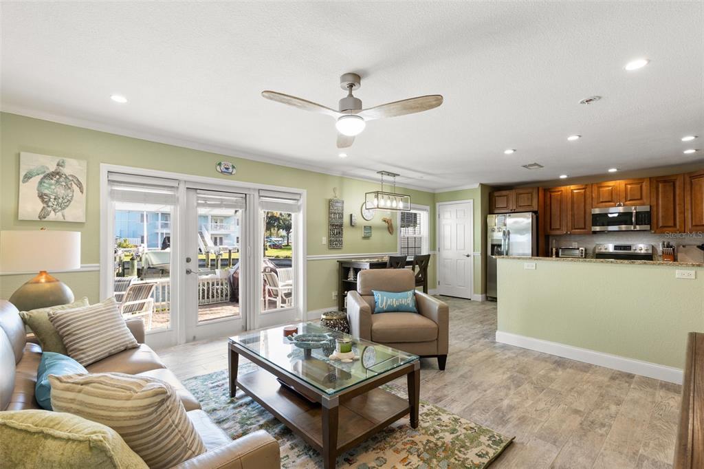 A living room and kitchen open-concept space features light green walls and wood-look tile flooring — 5243 BEACH DRIVE SE UNIT B, ST PETERSBURG, FL