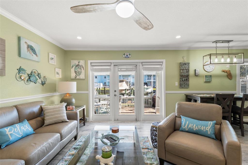 A living room with a leather sofa, armchair, ceiling fan, and glass doors to a patio — 5243 BEACH DRIVE SE UNIT B, ST PETERSBURG, FL