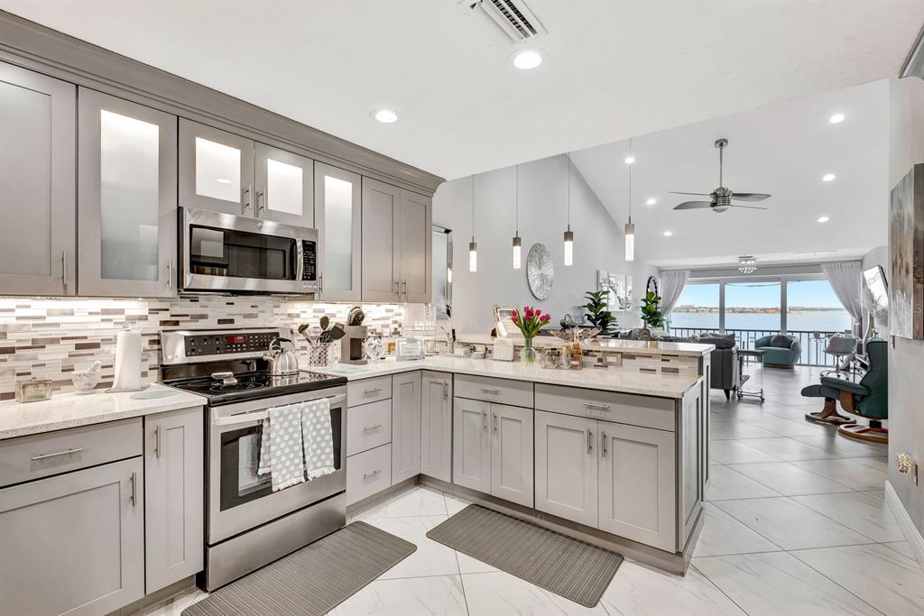 A modern kitchen with grey cabinets, stainless steel appliances, and a view of the water — 1602 STICKNEY POINT ROAD UNIT 404, SARASOTA, FL