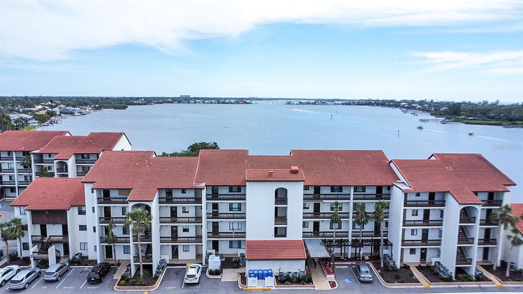 An aerial view shows a multi-story apartment building with a red tile roof near water — 1602 STICKNEY POINT ROAD UNIT 404, SARASOTA, FL