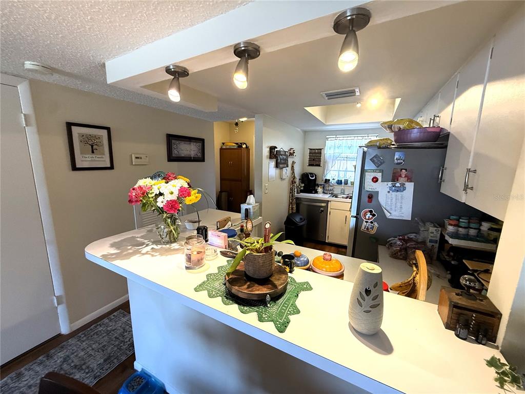 A kitchen features a breakfast bar, white cabinetry, and recessed lighting over the counter — 410 E ORLANDO AVENUE UNIT 19A, OCOEE, FL