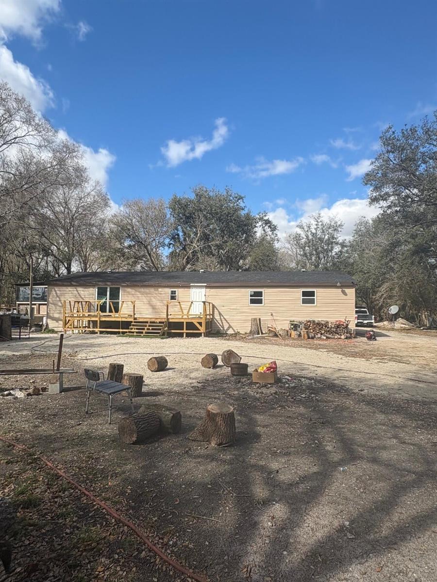 A single-story manufactured home with a wooden deck sits on a gravel lot — 20480 NW 294th Street, Okeechobee FL 34972, OKEECHOBEE, FL