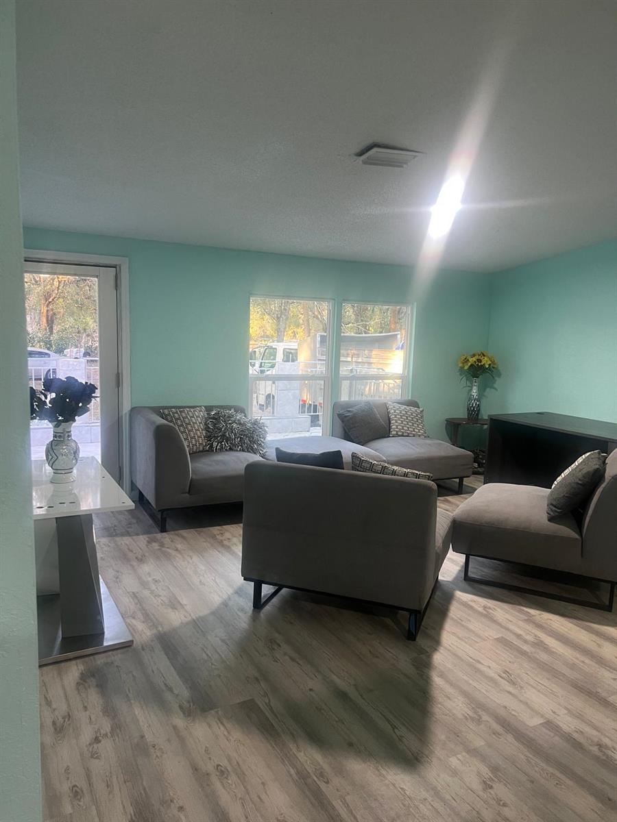 A living room with light blue walls, gray modular seating, and wood-look flooring — 20480 NW 294th Street, Okeechobee FL 34972, OKEECHOBEE, FL