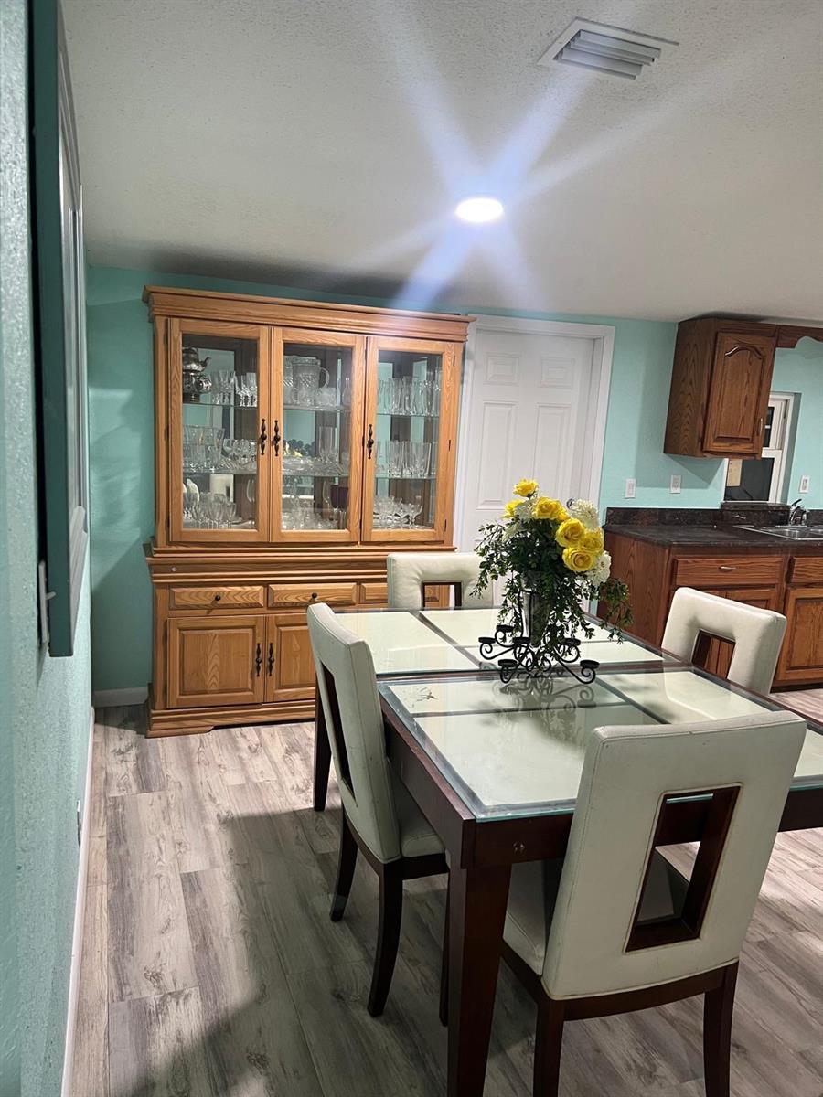 A dining area features a glass-top table, upholstered chairs, and a large wooden china cabinet — 20480 NW 294th Street, Okeechobee FL 34972, OKEECHOBEE, FL