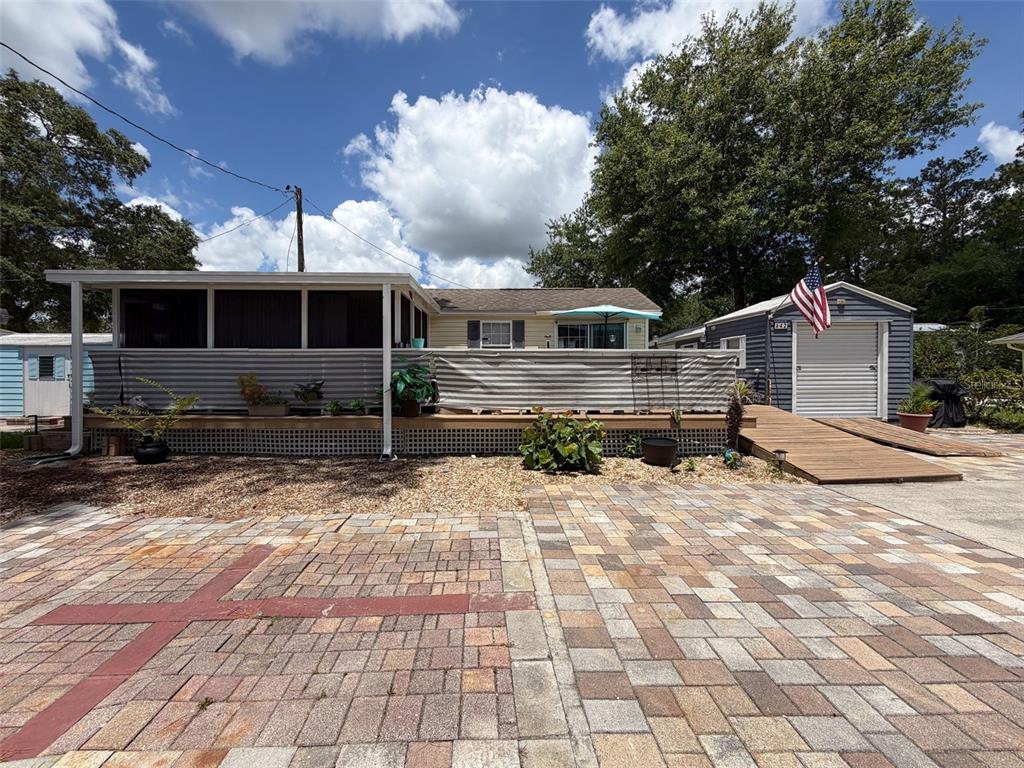 A manufactured home features a large screened porch, a wooden deck, and an adjacent shed — 2092 CULBREATH ROAD UNIT A42, BROOKSVILLE, FL