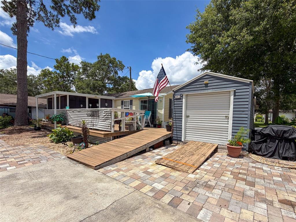 A house with a wooden ramp, a screened porch, and a shed with a roll-up door — 2092 CULBREATH ROAD UNIT A42, BROOKSVILLE, FL