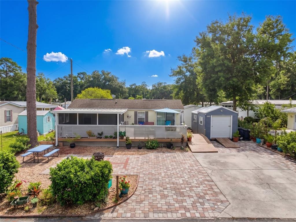 A single-story house with a screened porch, paver patio, and detached shed in a yard — 2092 CULBREATH ROAD UNIT A42, BROOKSVILLE, FL