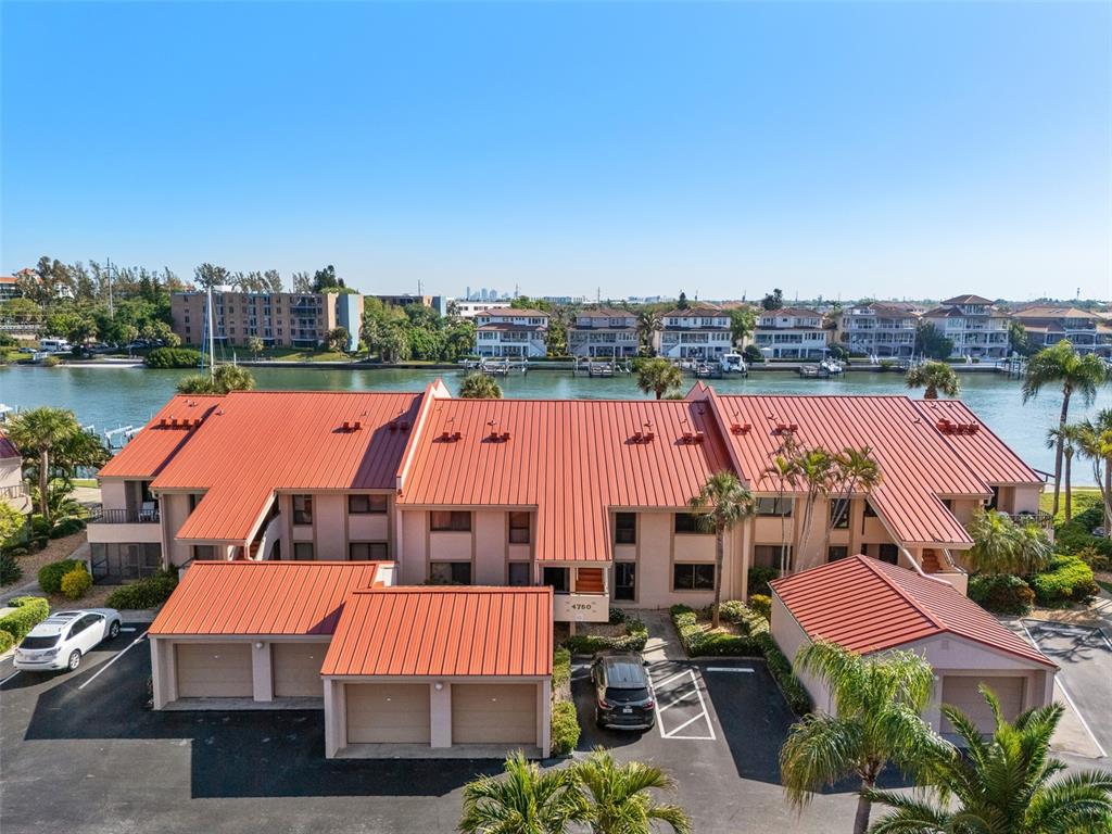 An aerial view shows a multi-unit residential building with a red metal roof — 4750 BRITTANY DRIVE S UNIT 126, ST PETERSBURG, FL