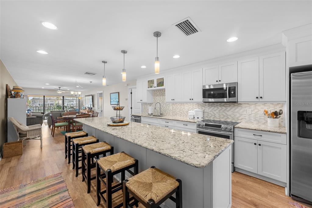 A modern kitchen with white cabinets, granite countertops, and a large island with bar seating — 4750 BRITTANY DRIVE S UNIT 126, ST PETERSBURG, FL