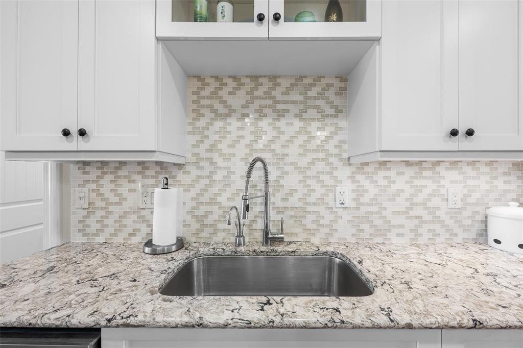 A kitchen sink with a stainless steel faucet sits against a patterned tile backsplash — 4750 BRITTANY DRIVE S UNIT 126, ST PETERSBURG, FL