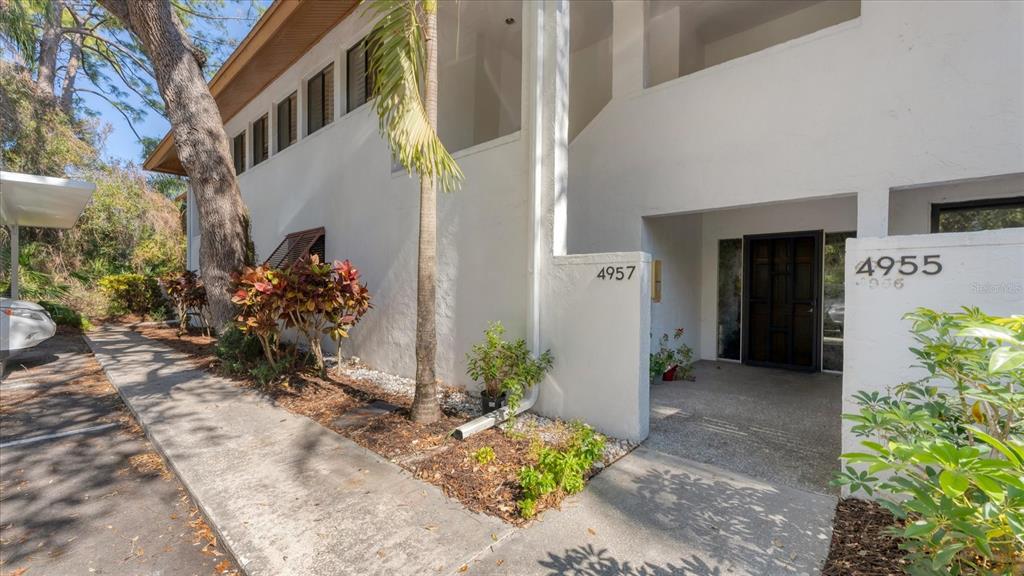 The exterior of a white two-story building features a covered entryway and a concrete walkway — 4957 CROSS CREEK ROAD UNIT 4957, SARASOTA, FL