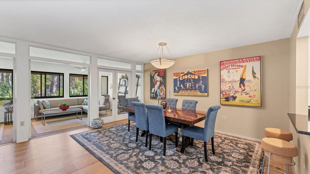 A dining room with a wooden table, blue chairs, and vintage circus posters on the wall — 4957 CROSS CREEK ROAD UNIT 4957, SARASOTA, FL