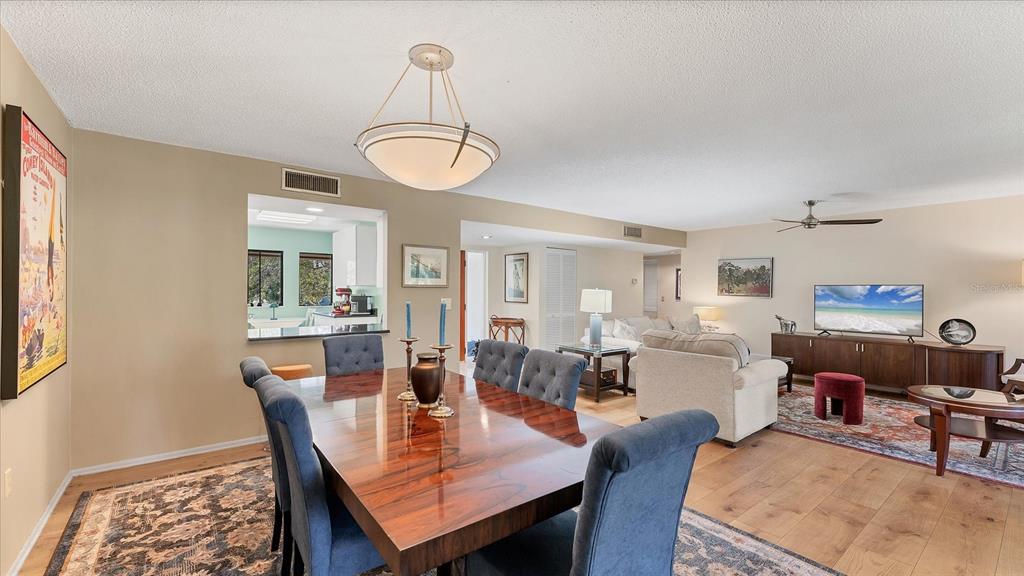 A dining area with a wooden table and blue chairs opens into a living room — 4957 CROSS CREEK ROAD UNIT 4957, SARASOTA, FL