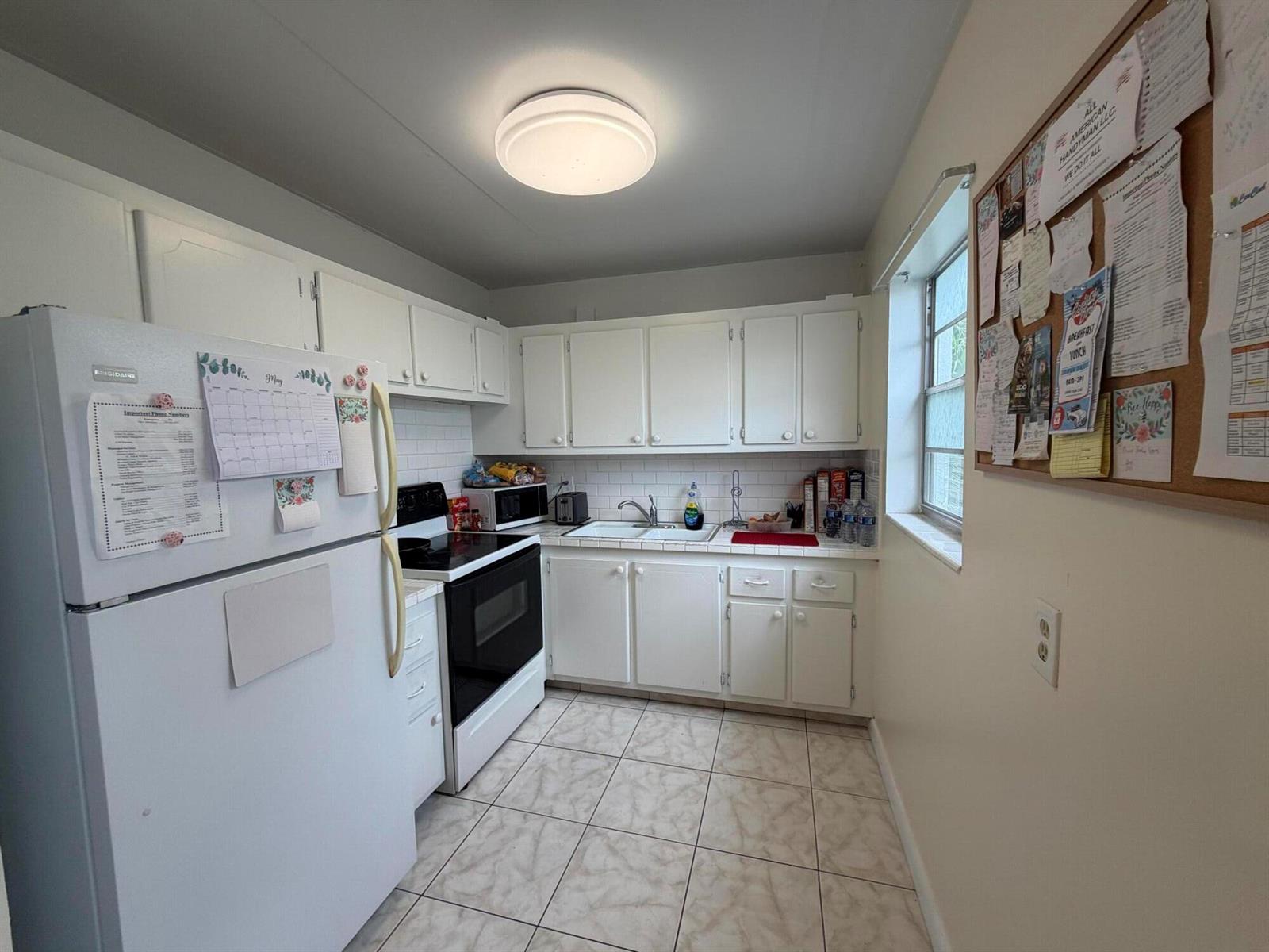 A small kitchen features white cabinets, white appliances, tiled countertops, and light-colored floor tiles — 229 E Durham E # 229, Deerfield Beach FL 33442, DEERFIELD BEACH, FL