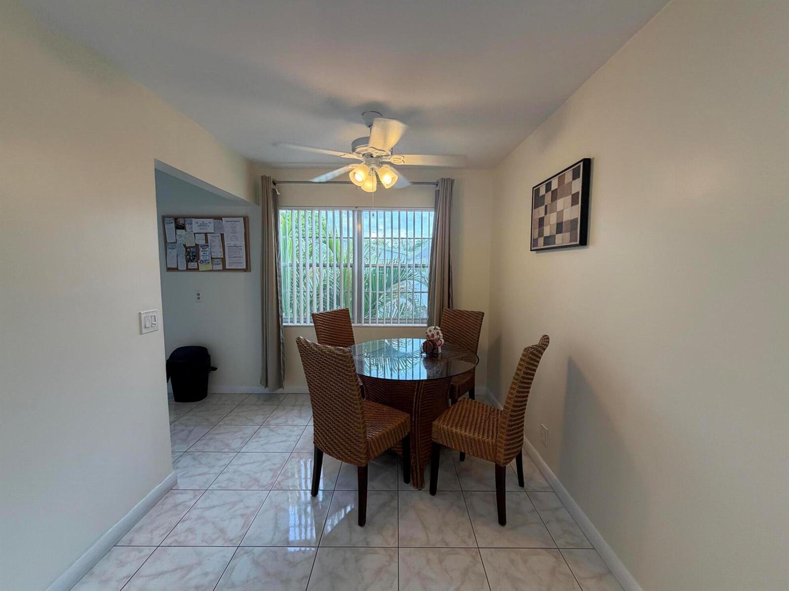 A dining area features a glass-topped table, four wicker chairs, tile flooring, and a ceiling fan — 229 E Durham E # 229, Deerfield Beach FL 33442, DEERFIELD BEACH, FL