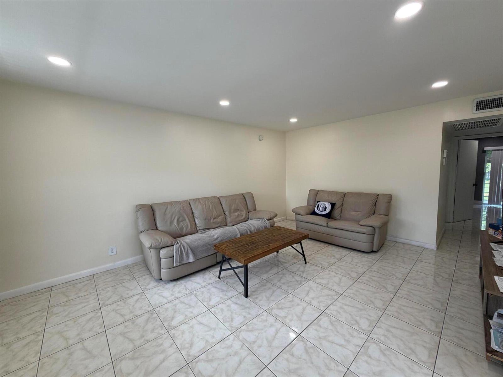 A living room features beige leather sofas, a wooden coffee table, and light-colored tile flooring — 229 E Durham E # 229, Deerfield Beach FL 33442, DEERFIELD BEACH, FL