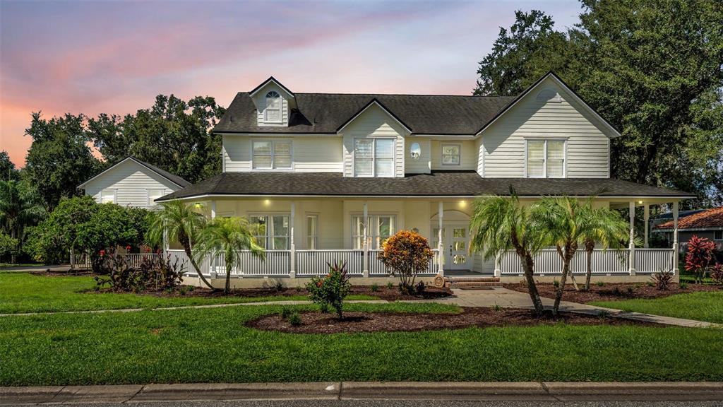 A two-story house with light siding and a wrap-around porch sits on a grassy lawn — 1632 REGAL COVE COURT, KISSIMMEE, FL