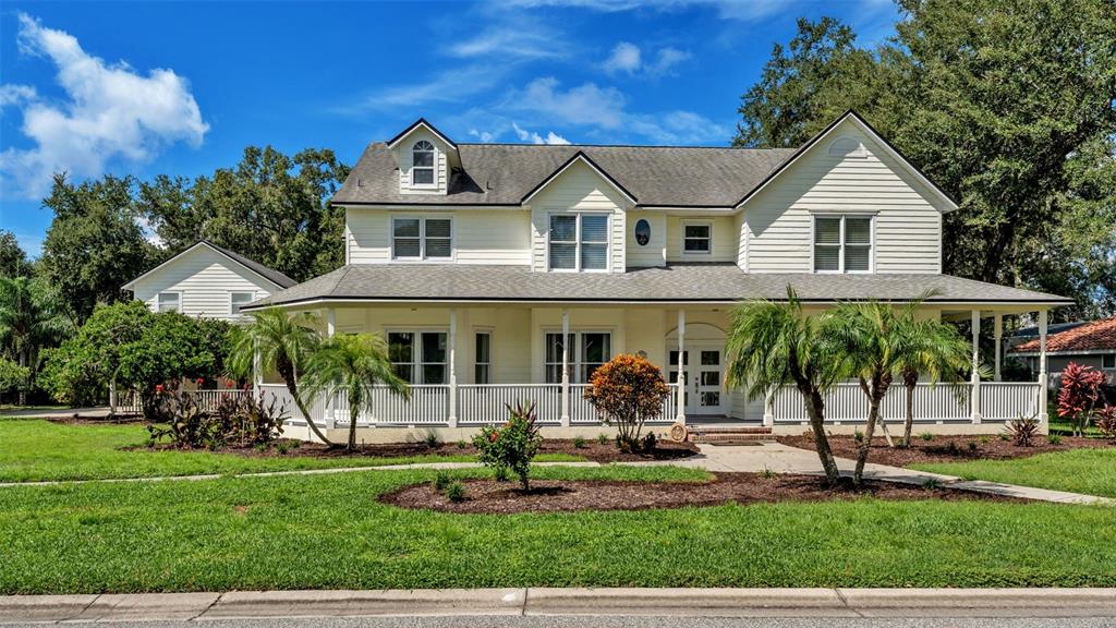 A two-story yellow house with a wrap-around porch and a detached garage — 1632 REGAL COVE COURT, KISSIMMEE, FL