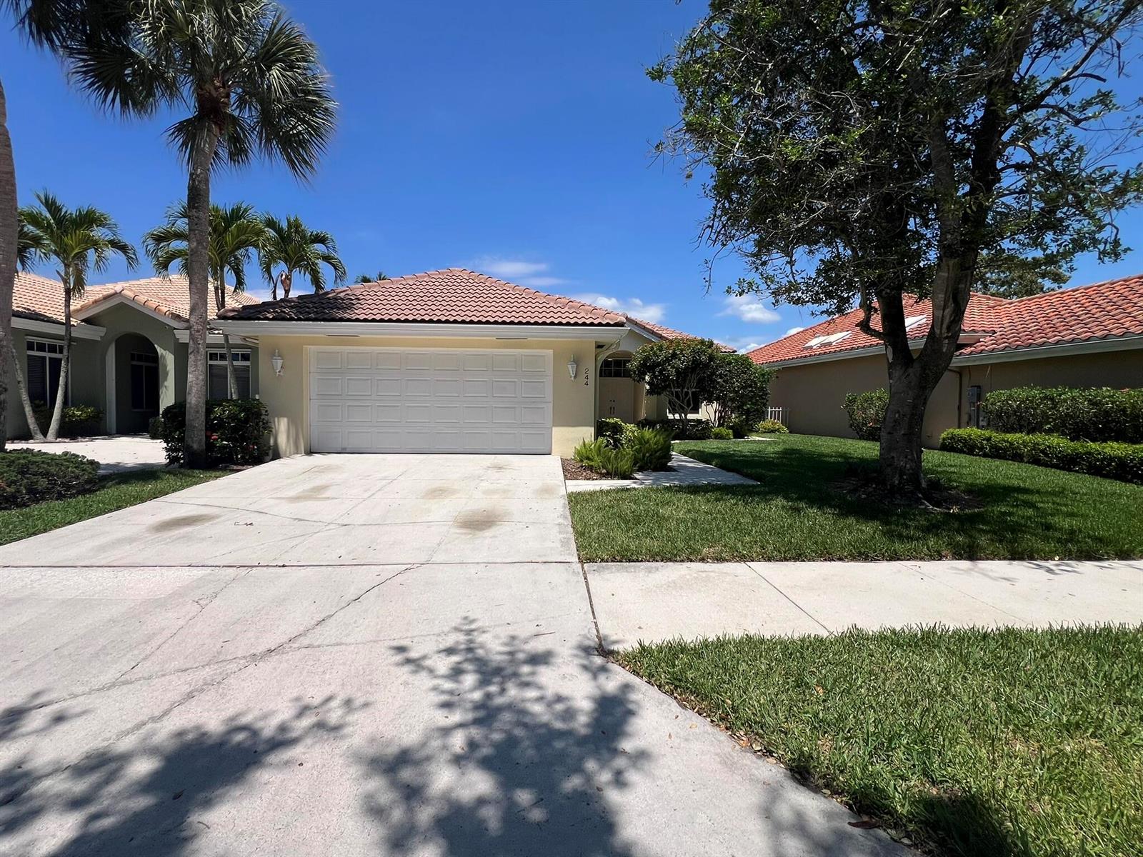 A single-story house with a tile roof, white garage door, and a concrete driveway — 244 Hampton Place, Jupiter FL 33458, JUPITER, FL