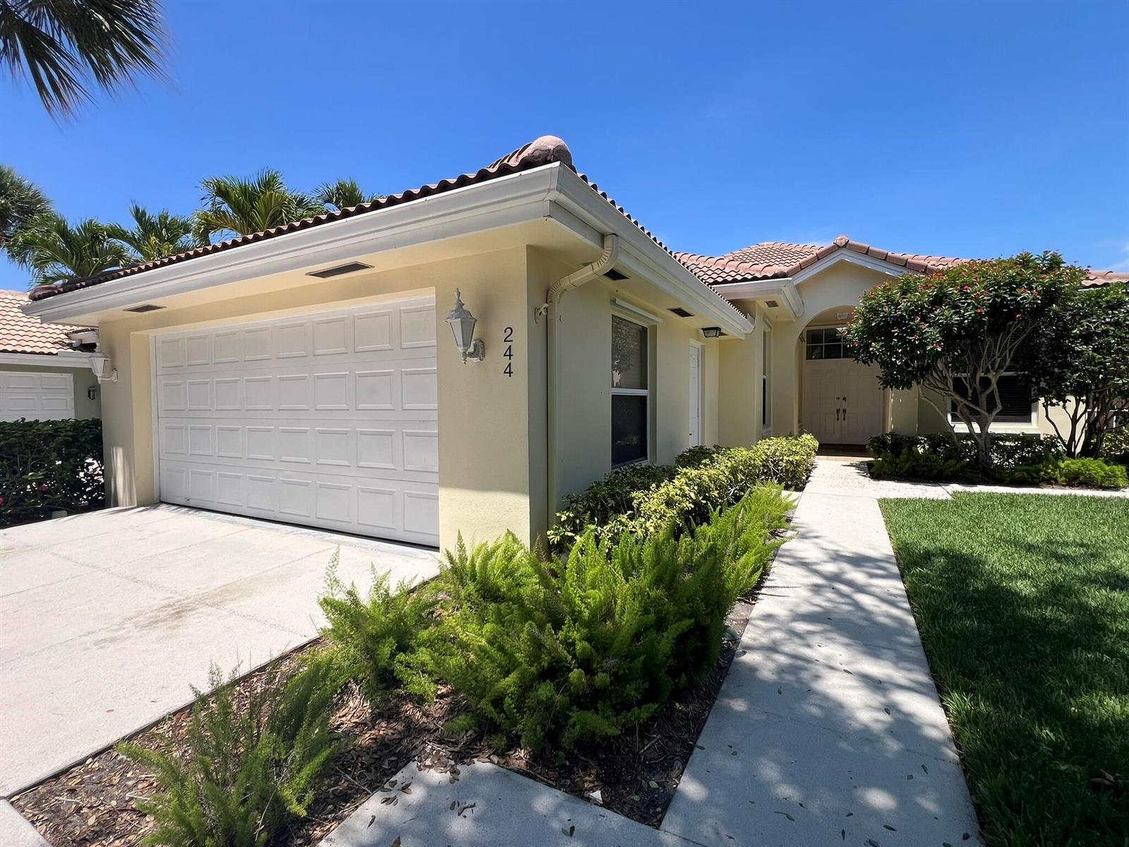 A light-colored single-story house features a two-car garage, a tiled roof, and a walkway — 244 Hampton Place, Jupiter FL 33458, JUPITER, FL
