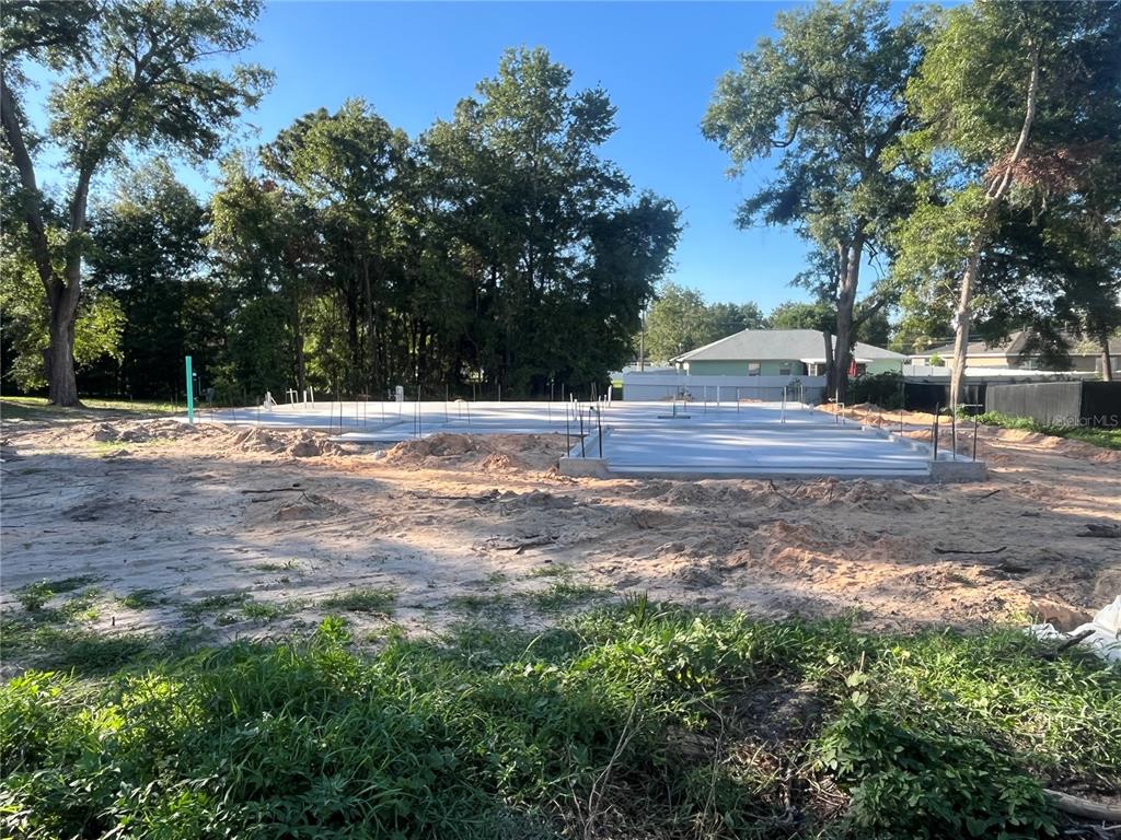 A concrete foundation slab sits on a cleared, sandy residential lot with surrounding trees — 18 HEMLOCK TERRACE TRL, OCALA, FL