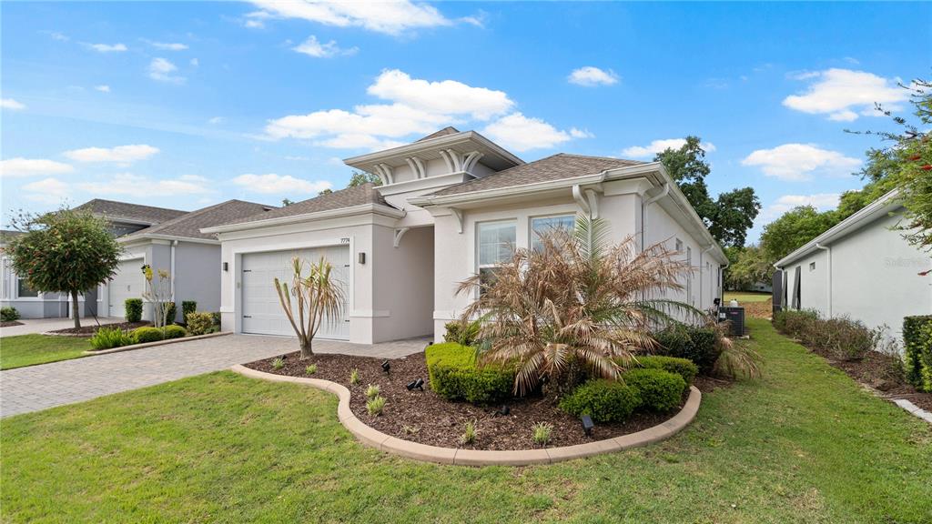 A single-story house with a beige stucco exterior, a two-car garage, and landscaped front yard — 7774 FOUR SEASONS BOULEVARD, KISSIMMEE, FL