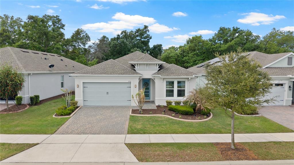 A single-story suburban house with a light-colored facade, a paved driveway, and a front garden — 7774 FOUR SEASONS BOULEVARD, KISSIMMEE, FL