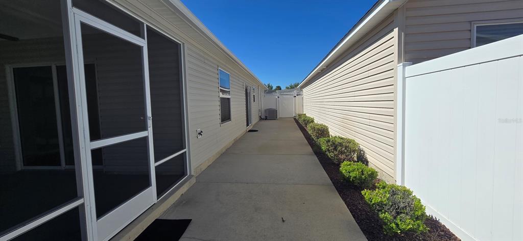 A concrete walkway runs between the side of a house and a white privacy fence — 2577 LINDEWOOD STREET, THE VILLAGES, FL