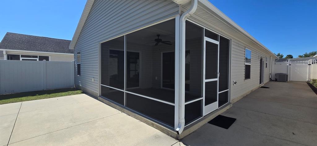 A screened-in patio with a ceiling fan sits on a concrete slab beside a house — 2577 LINDEWOOD STREET, THE VILLAGES, FL