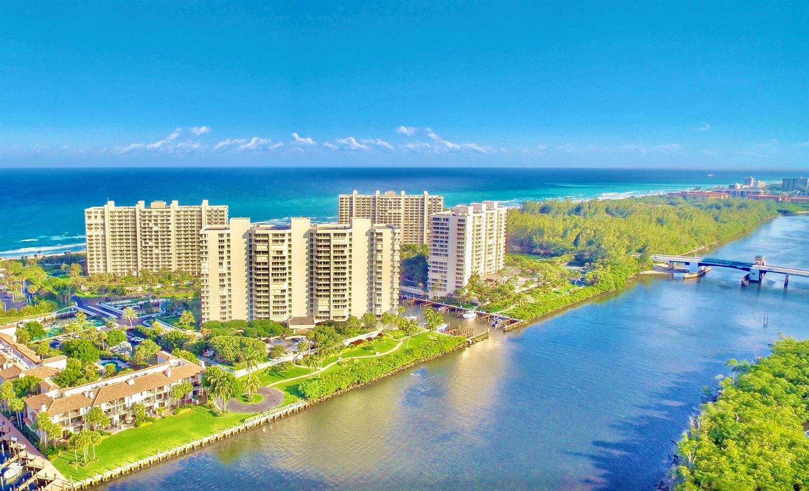 An aerial view shows high-rise apartment buildings situated between a river and the ocean — 4101 N Ocean Boulevard # 1604, Boca Raton FL 33431, BOCA RATON, FL
