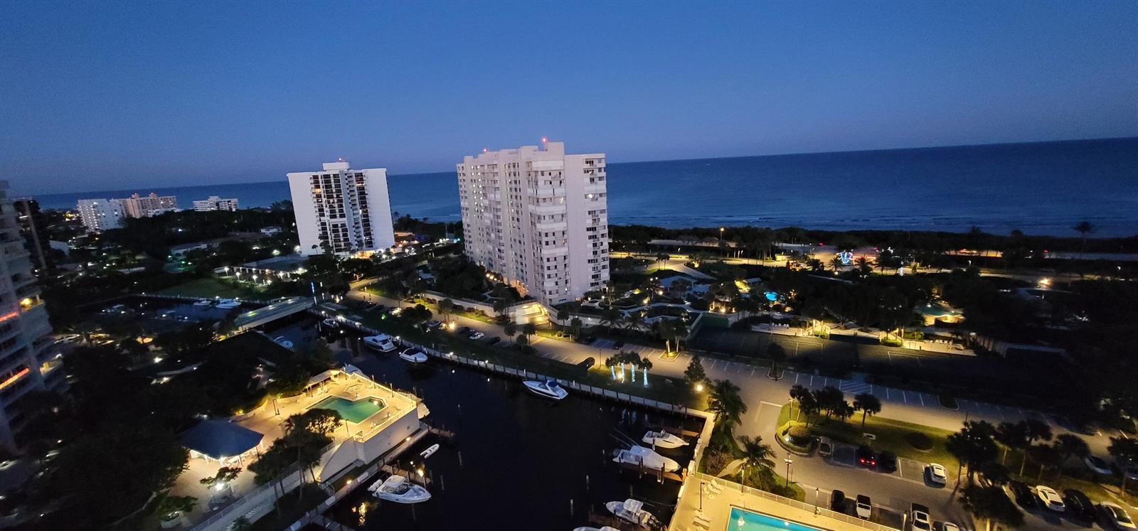 An elevated night view of a coastal residential area featuring high-rise buildings, boats, and pools — 4101 N Ocean Boulevard # 1604, Boca Raton FL 33431, BOCA RATON, FL