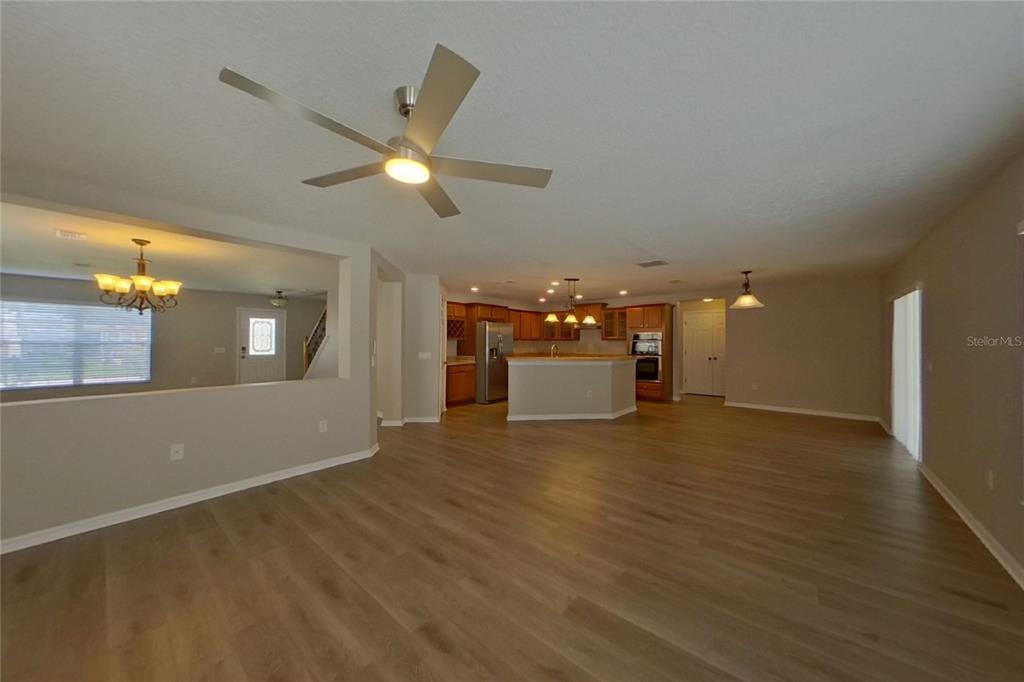 An open-concept living area features light wood-look flooring, a ceiling fan, and a kitchen island — 4667 CAVERNS DRIVE, KISSIMMEE, FL