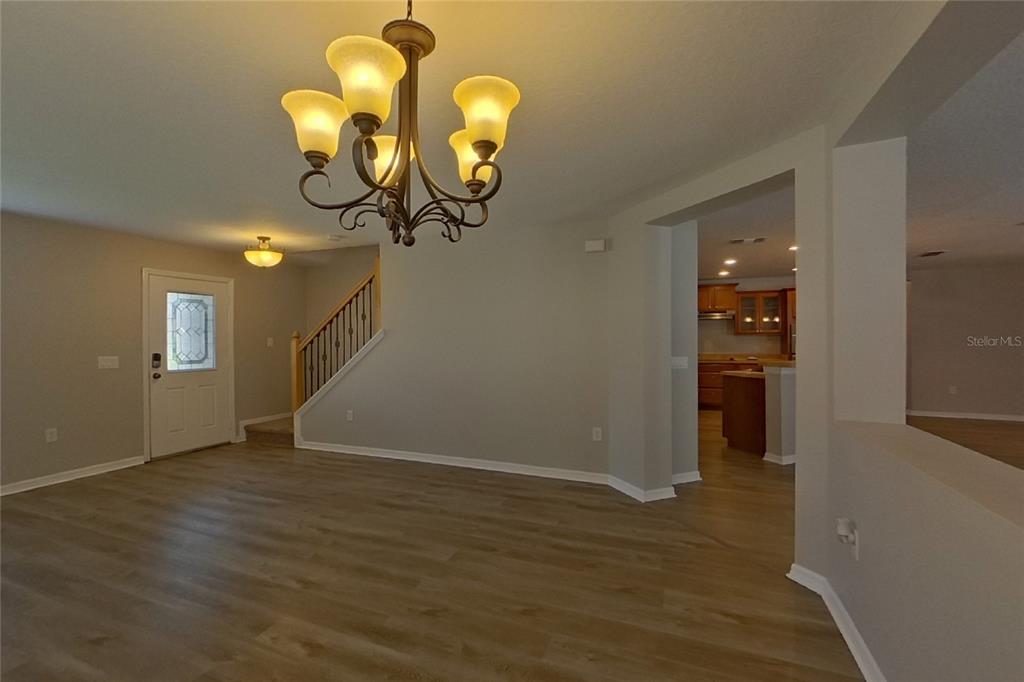 A foyer with wood-look flooring, a chandelier, and a staircase leading to an upper level — 4667 CAVERNS DRIVE, KISSIMMEE, FL