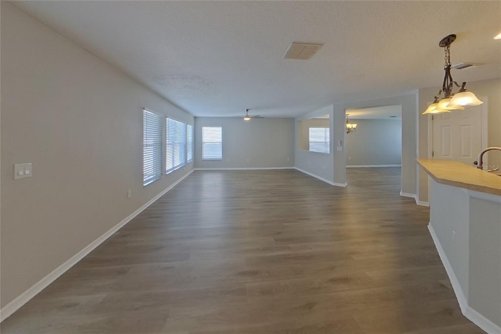 An open-concept living area features light gray walls, wood-look flooring, and a kitchen breakfast bar — 4667 CAVERNS DRIVE, KISSIMMEE, FL