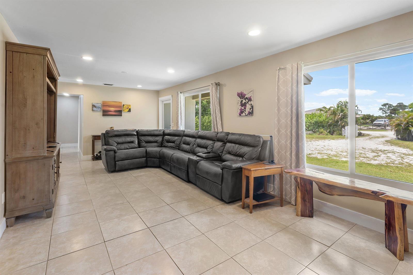 A living room features a large gray sectional sofa, tile flooring, and a wooden bench — 12944 68th Street N, FL 33412, FL