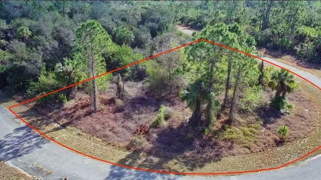 An aerial view shows a vacant, wooded corner lot outlined in red along a paved road — 1148204901 ASHBORO CIRCLE, NORTH PORT, FL