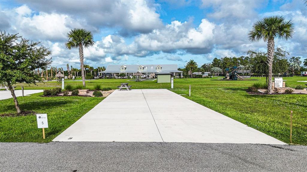 A concrete RV pad sits in a grassy park with a clubhouse in the background — 0 HIGHWAY 630 E UNIT 5, LAKE WALES, FL