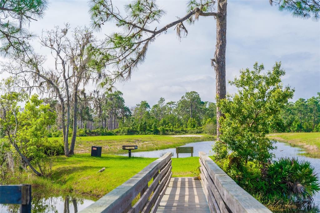 A wooden footbridge leads to a grassy area with a bench and a small pond — 0 HIGHWAY 630 E UNIT 5, LAKE WALES, FL